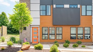 Un moderno edificio de dos pisos con fachada de ladrillo, ventanas grandes y una puerta naranja.