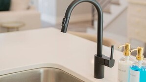Una cocina moderna con un lavamanos de acero inoxidable, un grifo negro y dos botellas de jabón sobre la encimera.