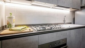 Une cuisine moderne équipée d’une cuisinière à gaz, d’un évier et d’une planche à découper en bois, avec un torchon vert.