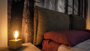 Une chambre à coucher avec un lit, une table de chevet et une lampe fixée au mur.
