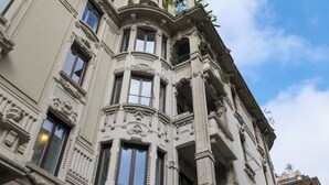 A corner of a building with ornate architectural details, large windows, and balconies.