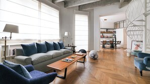 A spacious living room with a sofa, chairs, a coffee table, and a bookshelf.