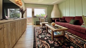 A cozy living room with a wooden coffee table, a red sofa, and a television on a wooden stand. - Cozy 2 bedroom flat with beautiful views (Cortina d'Ampezzo)