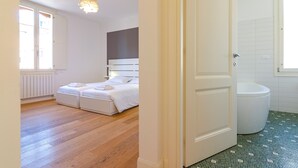 Een slaapkamer met een bed, een nachtkastje, een raam en een deur naar een badkamer.