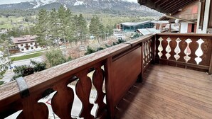 A wooden balcony with a view of a mountain range and a town below. - Classy 3 bedroom few steps from centre (Cortina d'Ampezzo)