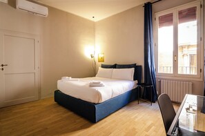 A bedroom with a bed, a bedside table, a chair, and a window with curtains. - Luxury 2bed apartment in top location (Bologna)