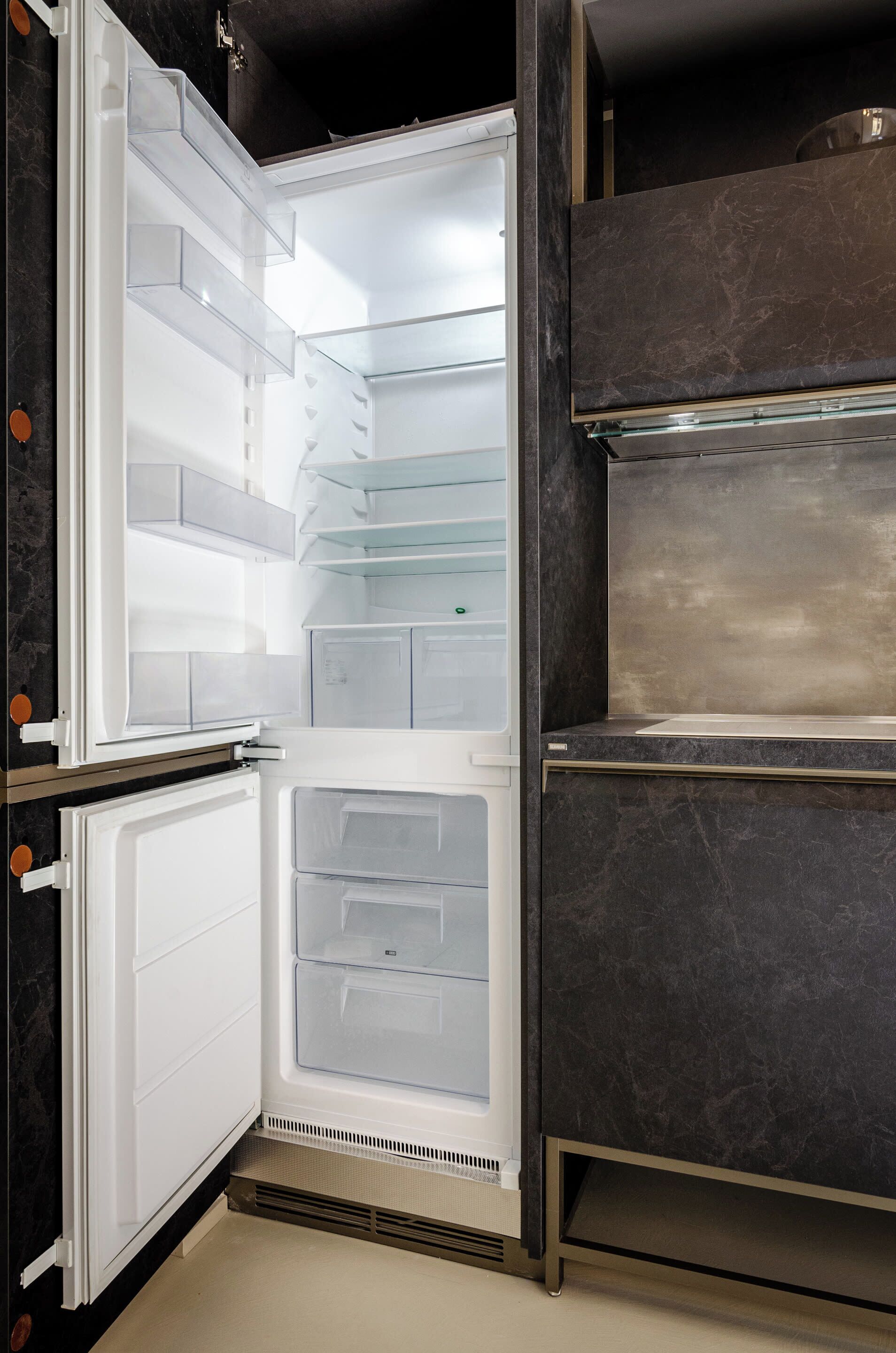 Un refrigerador abierto con varios estantes transparentes y un compartimento congelador.