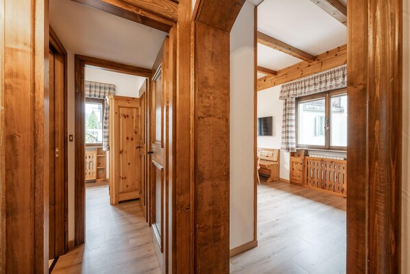 A wooden interior hallway with a view into a kitchen area.