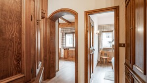 A wooden hallway leading to a kitchen with a dining area.