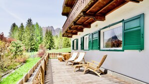 Eine Holzterrasse mit Liegestühlen und einem Tisch mit Blick auf eine gebirgige Landschaft.