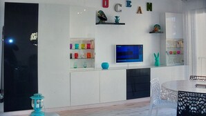 Una sala de estar moderna con televisor, estanterías con objetos decorativos y la palabra 'OCEAN' escrita en la pared.