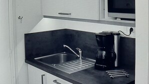 Una cocina compacta equipada con microondas, cafetera y lavabo.