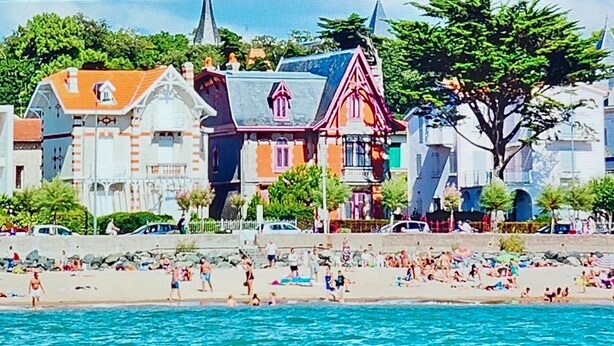 Un pueblo costero con playa, edificios históricos y un mar azul cristalino.