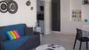 Una sala de estar con un sofá gris, una mesa de centro redonda y una estantería.