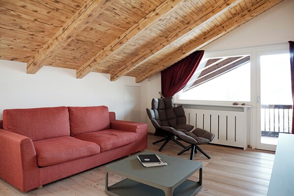 Una sala de estar moderna con un sofá rojo, una mesa de centro gris y un sillón marrón.
