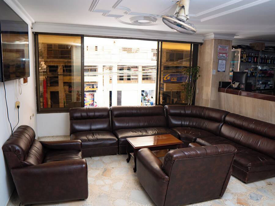 Una sala de estar en esquina con un sofá modular, una mesa de centro y un televisor montado en la pared.