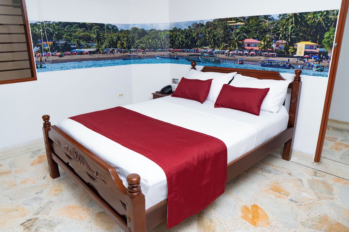 Un lit avec un cadre en bois, du linge de lit blanc et des oreillers rouges.