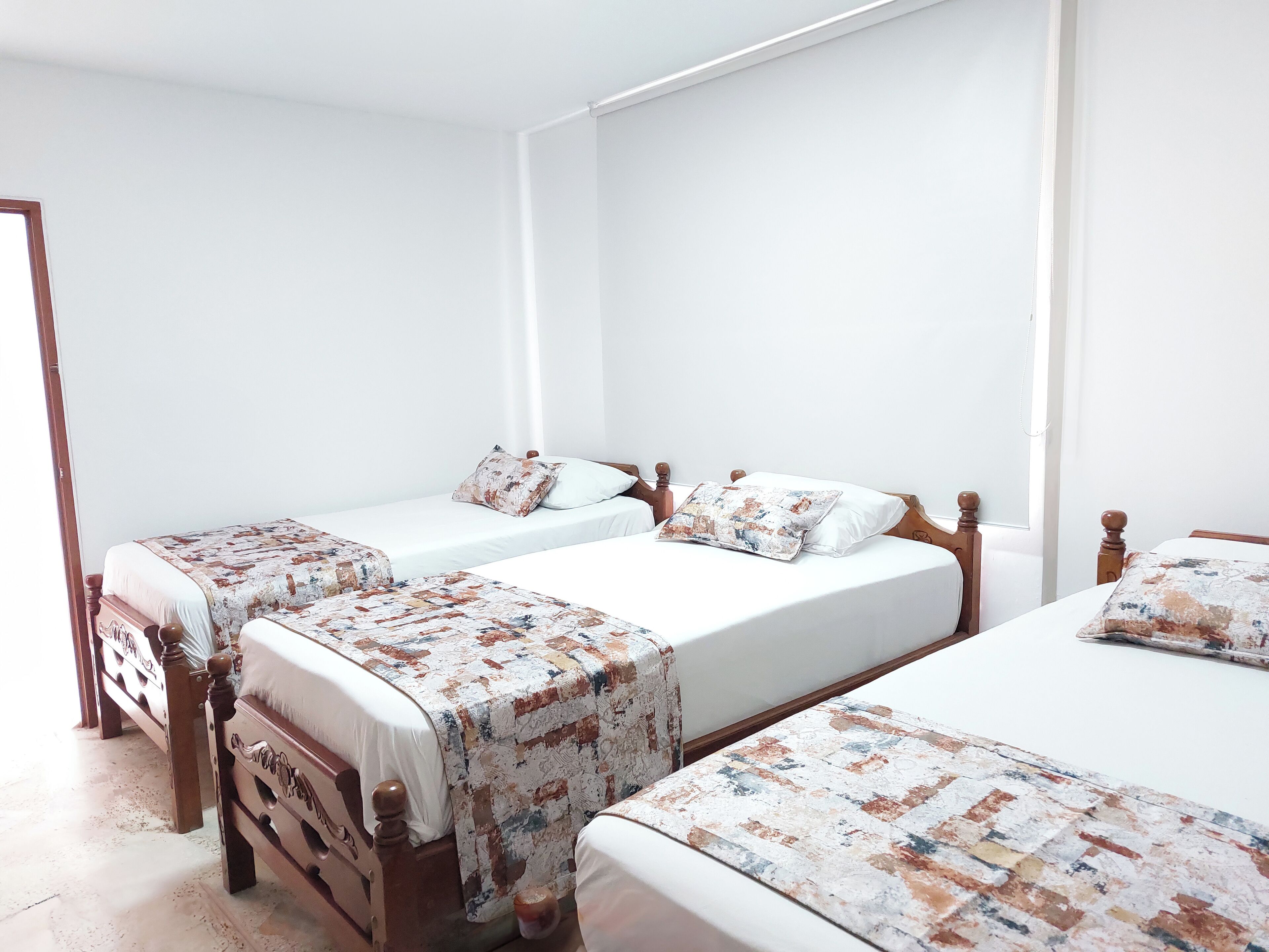 A hotel room with two single beds, each with a wooden headboard and a floral-patterned bedspread.