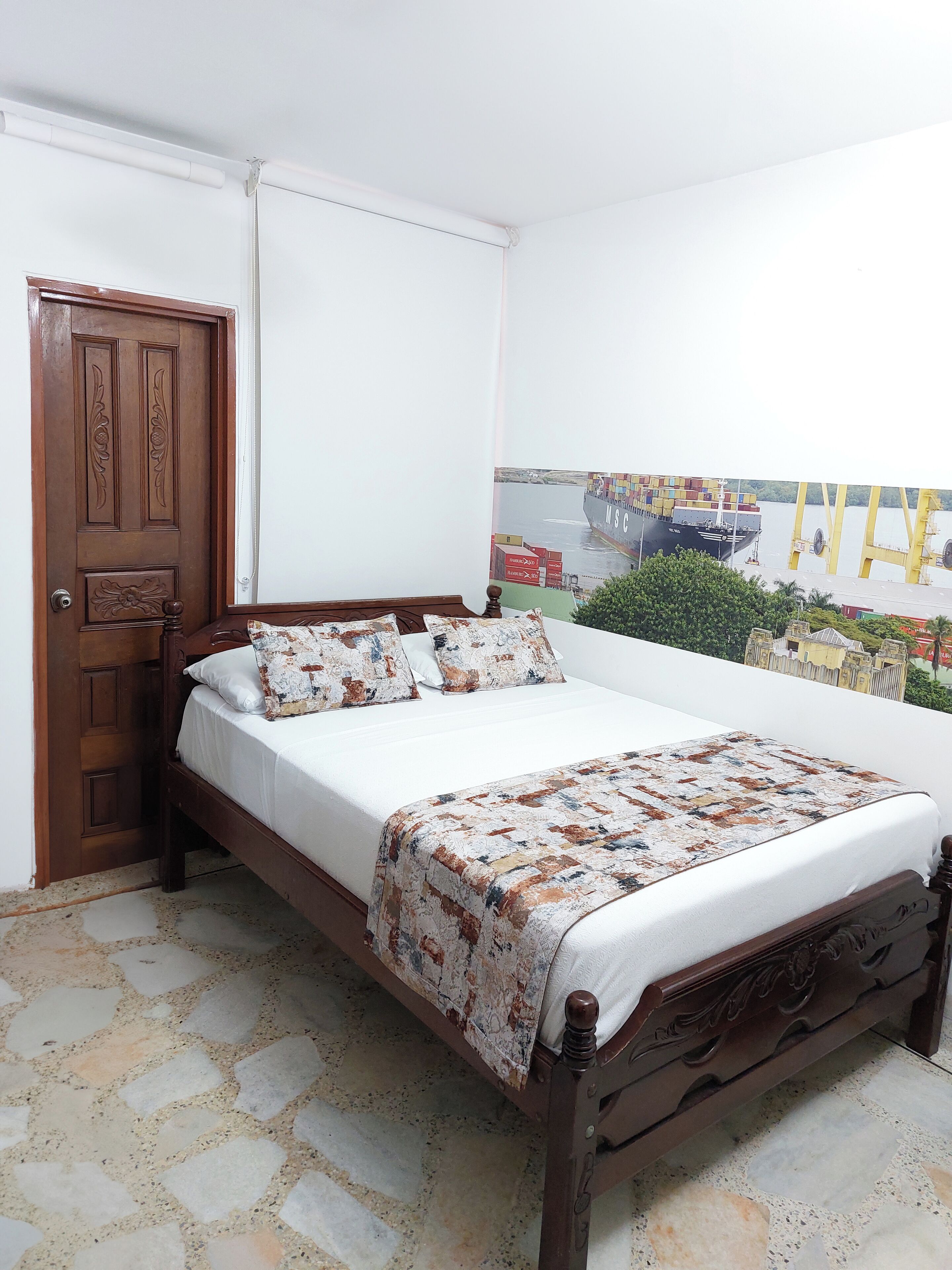 A bedroom with a wooden bed, white bedding, and a patterned throw.