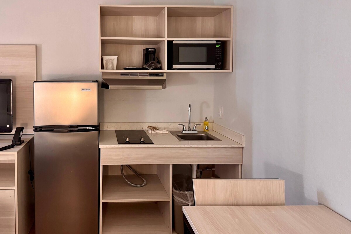 Une petite cuisine équipée comprenant un réfrigérateur, un four à micro-ondes, un évier et une petite table.