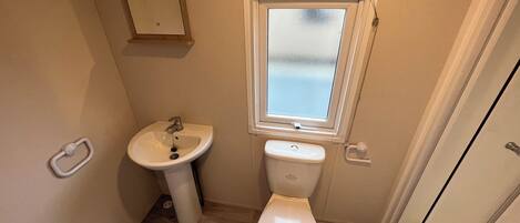 A small bathroom with a sink, toilet, and window.