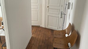 A hallway with wooden flooring, white walls, and a door with a picture frame. - Apartment in lively neighborhood near Marais.  (Paris)