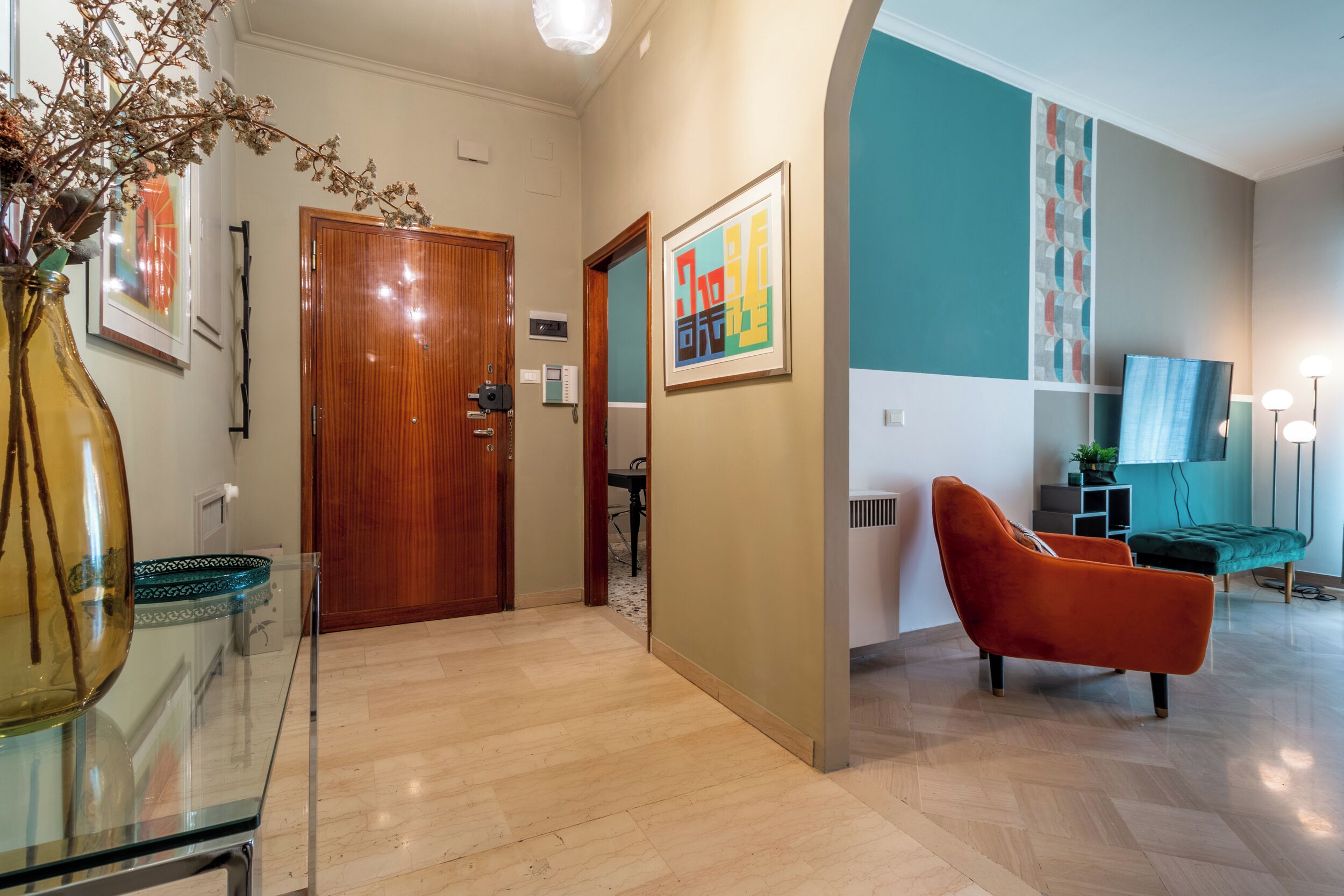 Una sala de estar moderna con un piso de madera, una mesa de centro de vidrio, un sofá rojo y una pared de acento color verde azulado.
