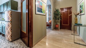 A modern kitchen with patterned appliances, a wooden door, and a hallway leading to a seating area.