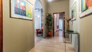 A hallway with framed artwork, a potted plant, and a glass table.