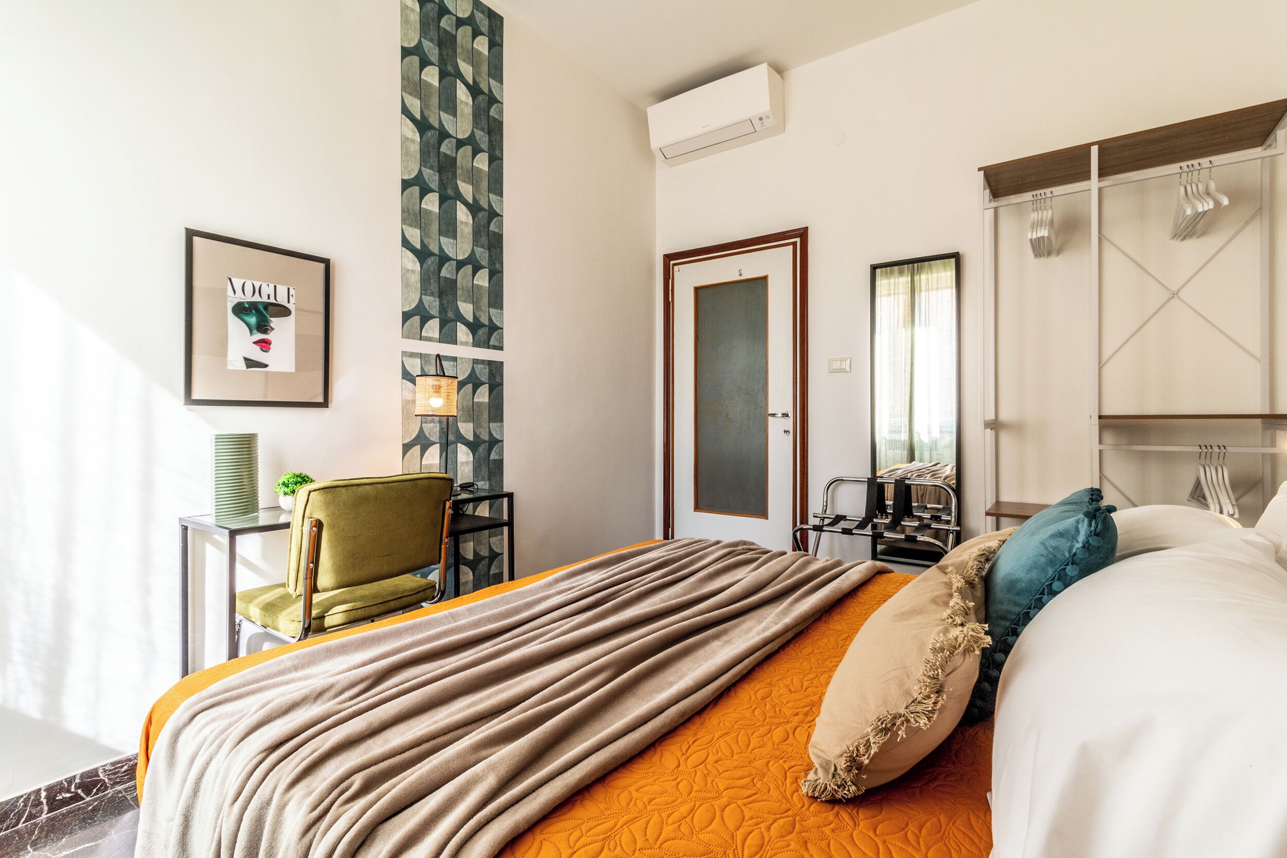 A hotel room with a bed, a chair, a desk, and a wardrobe.