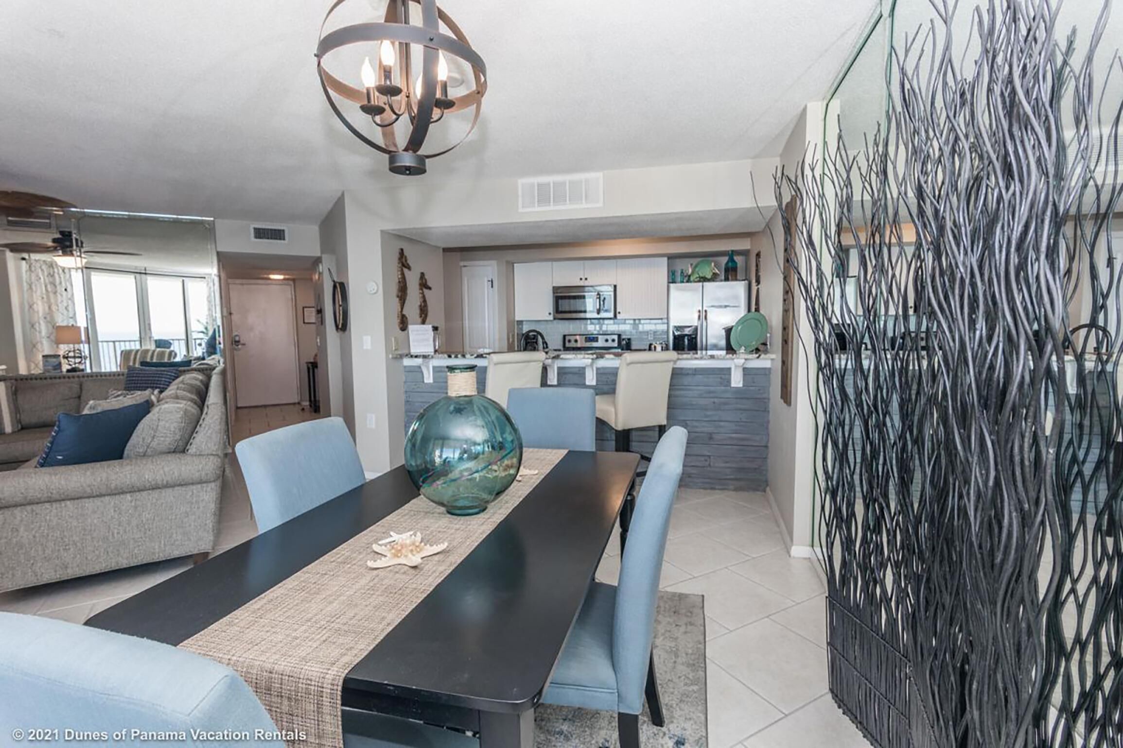 A modern living room with a dining table, sofas, and a kitchen in the background.