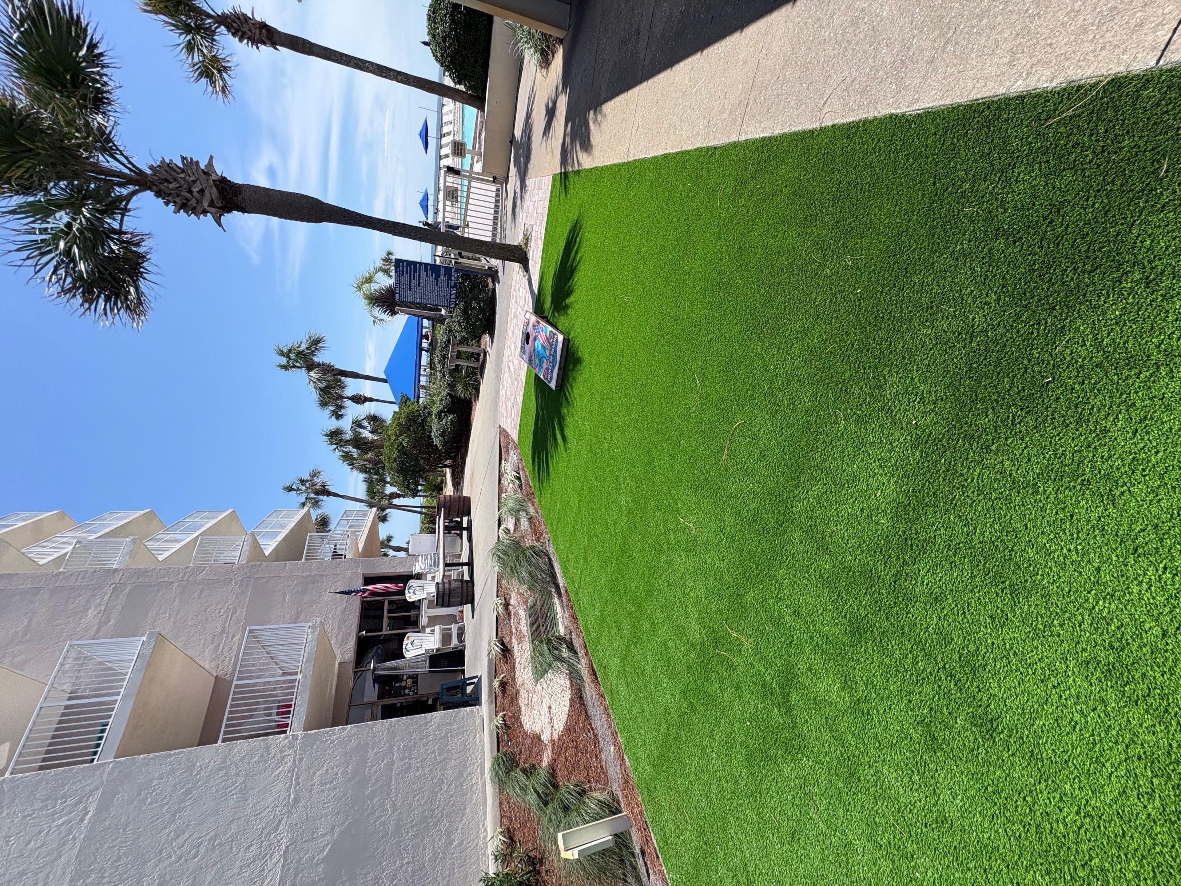 A hotel with a green lawn, palm trees, and a building with a modern design.