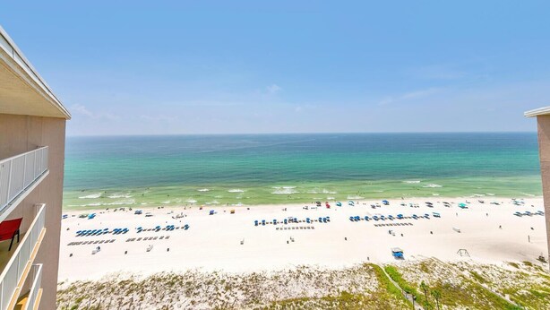 A beach view from a balcony with a clear sky, sandy beach, and ocean. - Dunes of Panama 2104e (Panama City Beach)