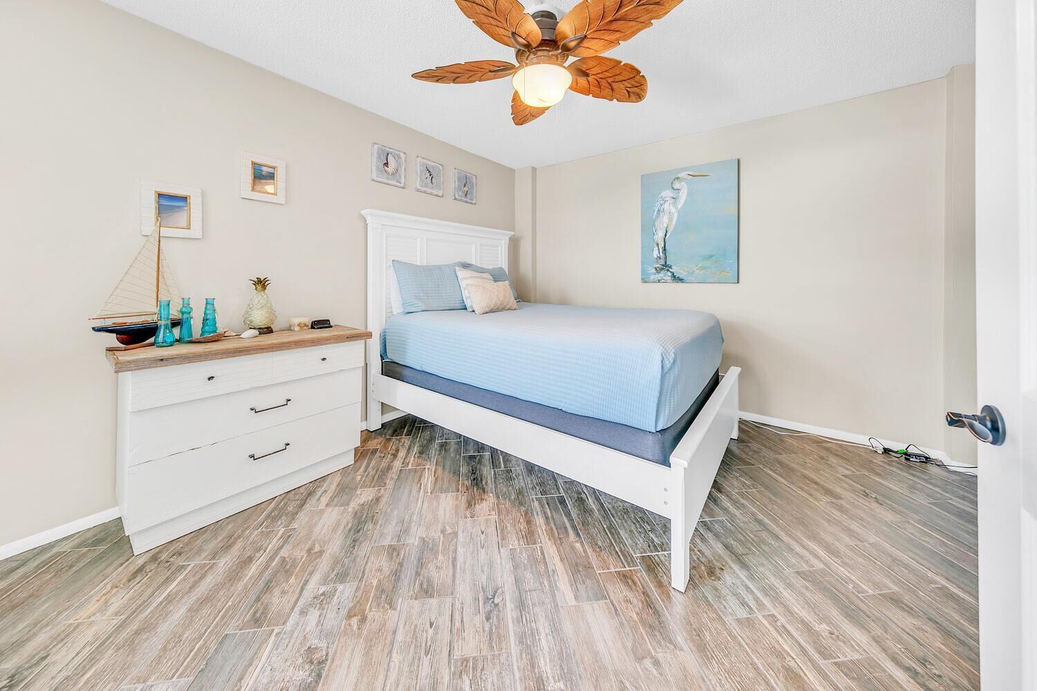 A bedroom with a bed, a nightstand, a dresser, and a ceiling fan.