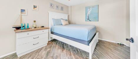 A bedroom with a bed, a nightstand, a dresser, and a ceiling fan.