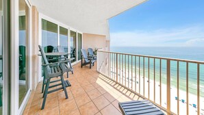 A balcony with a view of the beach and ocean. There are chairs and a table on the balcony. - Dunes of Panama 2104e (Panama City Beach)