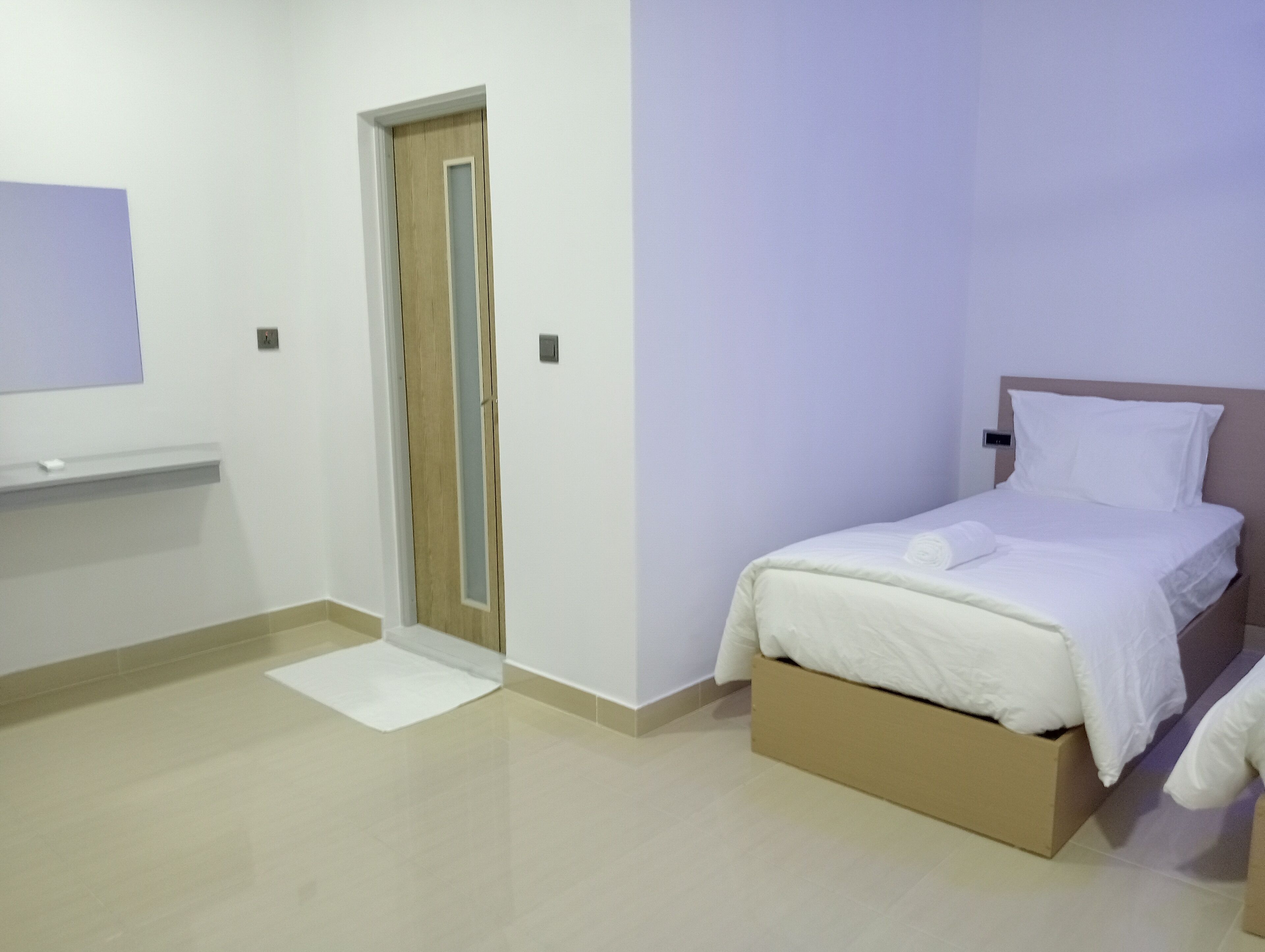Ein Schlafzimmer mit einem Bett, einer Tür und einem kleinen weißen Regal.