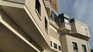 A modern building with a flat roof, multiple windows, and a staircase leading to an upper level. - My Motel (Paisley)