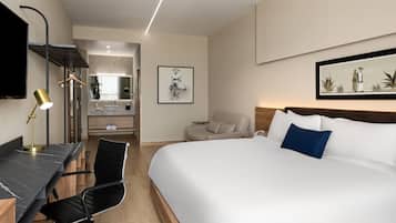 Una habitación de hotel con cama, escritorio, silla y televisión.
