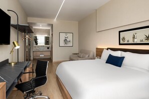 Una habitación de hotel con cama, escritorio, silla y televisión.