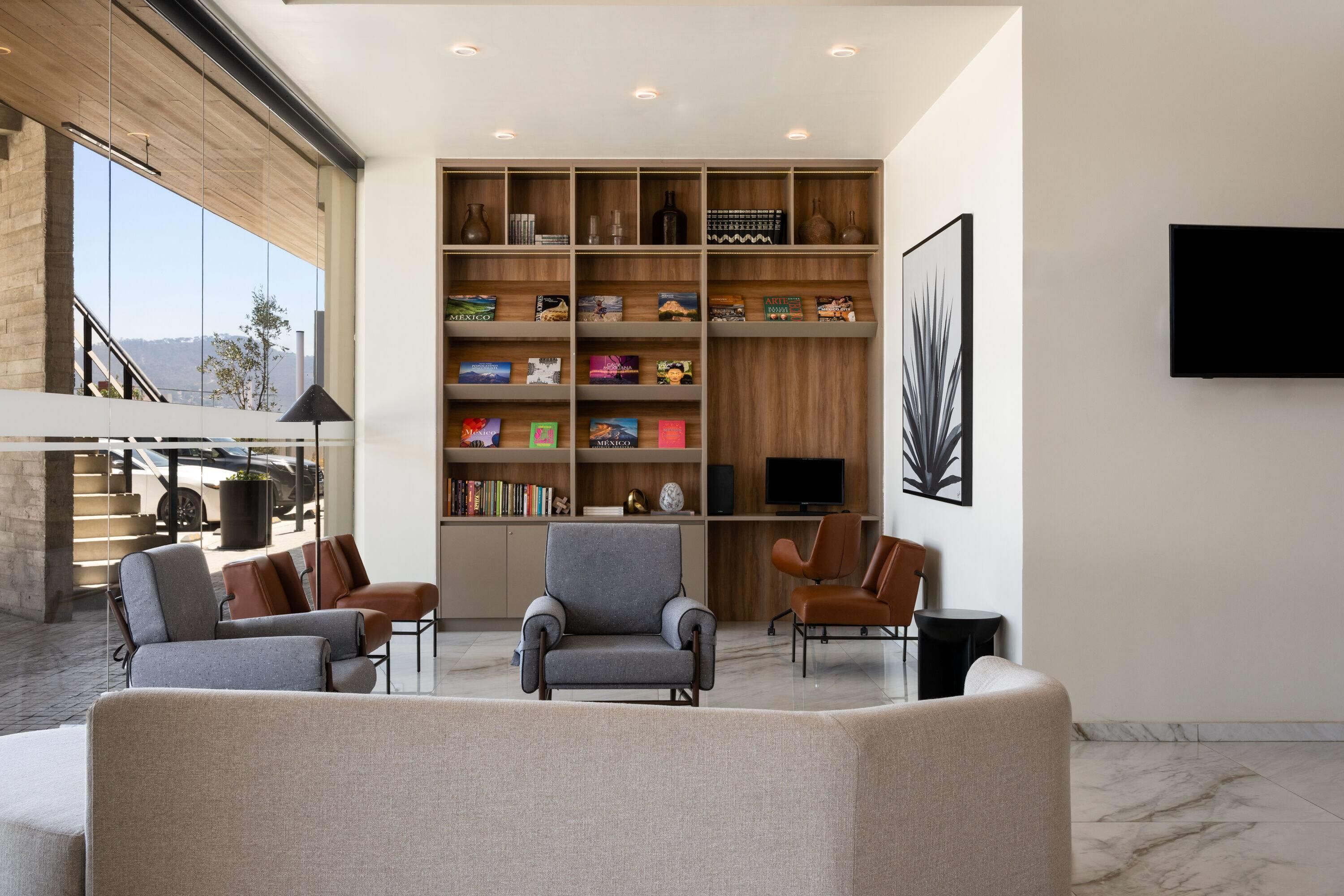 A modern living room with a large bookshelf, comfortable seating, and a flat-screen TV.