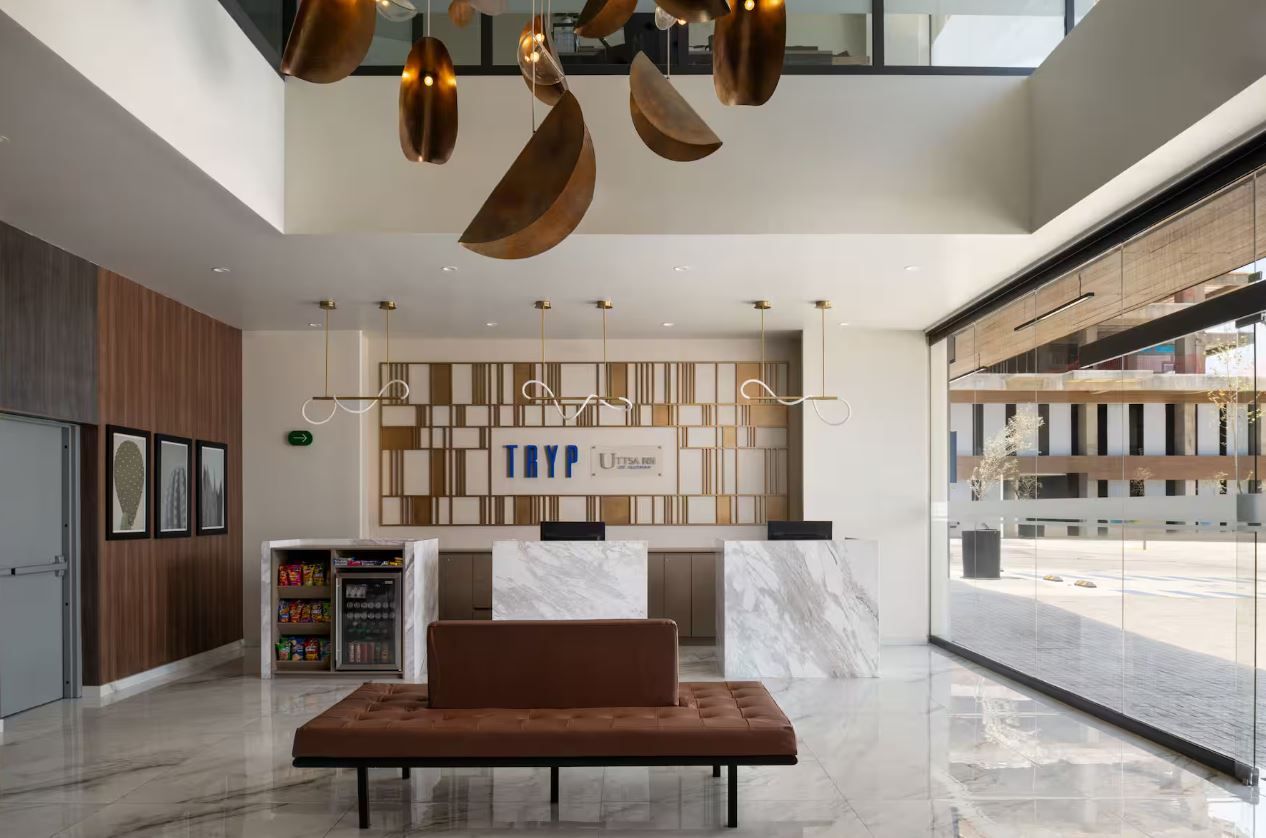 Eine moderne Lobby mit einer Rezeption, einer Sitzgelegenheit und einem großen Fenster mit Blick auf die Straße.