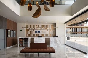 Una hall moderna con reception, area salotto e un'ampia finestra vista strada.