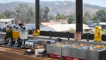 Montaje de buffet con diversos alimentos y vistas del paisaje circundante.