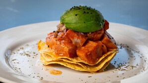 Um prato com comida, base de tortilha coberta com vegetal verde e molho vermelho.