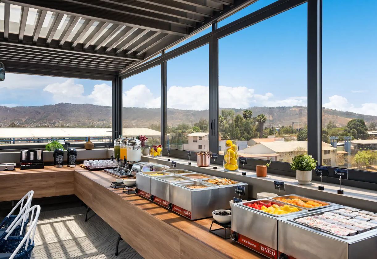 A buffet area with various food options, a seating area, and a view of the landscape through large windows.