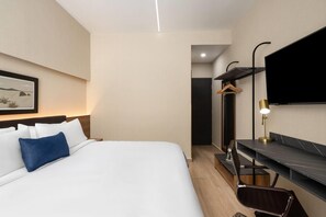 Een hotelkamer met een groot bed, een bureau met stoel, een flatscreen televisie en een ingelijste foto aan de muur.
