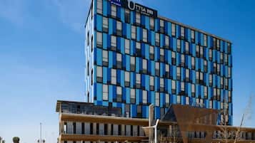 Un moderno edificio de hotel con fachada azul y negra, múltiples ventanas y un letrero que dice "UTTSA INN".