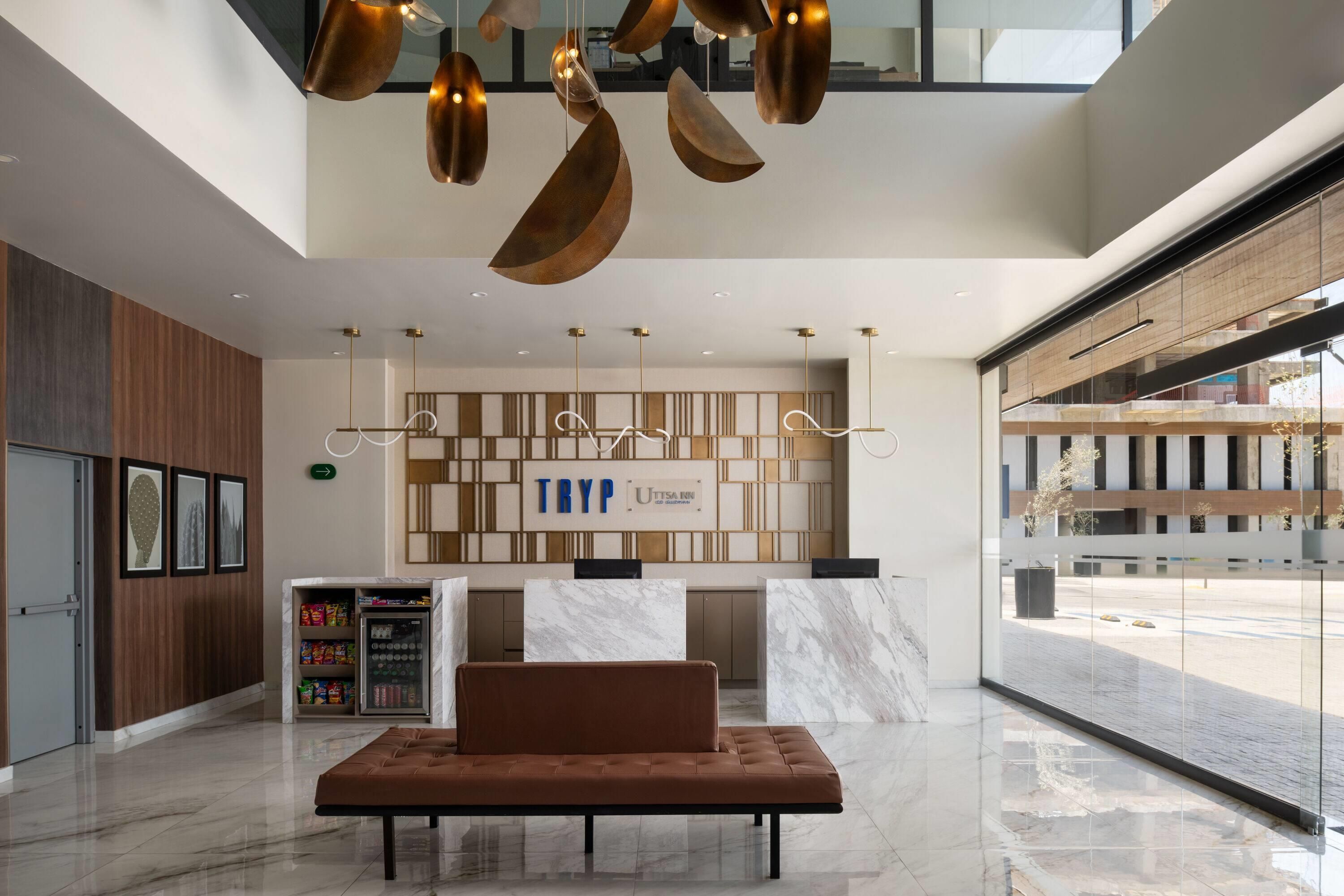 A modern lobby with a reception desk, seating area, and a vending machine.