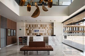 Eine moderne Lobby mit Empfangstresen, Sitzgelegenheiten und einem Getränkeautomaten.